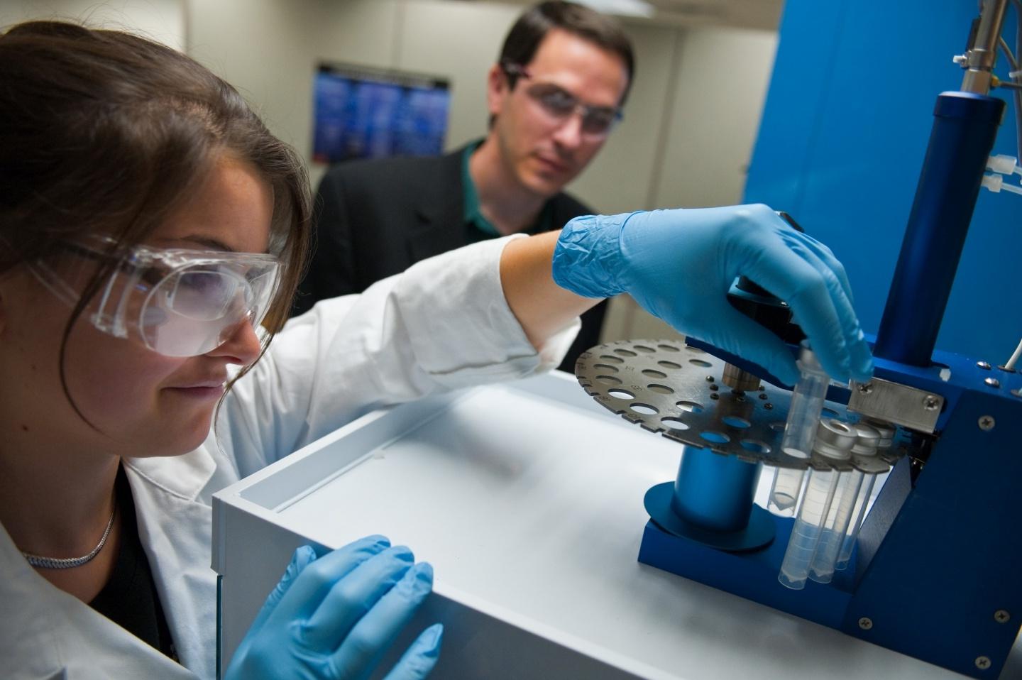 Student working with a test tube as professor observes